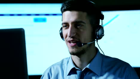 Un-hombre-joven,-que-trabaja-en-servicio-al-cliente-o-en-alguna-estación-de-torre-de-control-del-aeropuerto,-responde-a-las-llamadas-a-los-clientes-de-teléfono-con-una-sonrisa-día-y-noche.