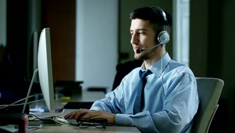 Un-hombre-joven,-que-trabaja-en-servicio-al-cliente-o-en-alguna-estación-de-torre-de-control-del-aeropuerto,-responde-a-las-llamadas-a-los-clientes-de-teléfono-con-una-sonrisa-día-y-noche.