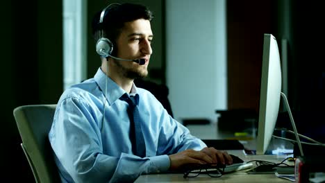 Un-hombre-joven,-que-trabaja-en-servicio-al-cliente-o-en-alguna-estación-de-torre-de-control-del-aeropuerto,-responde-a-las-llamadas-a-los-clientes-de-teléfono-con-una-sonrisa-día-y-noche.