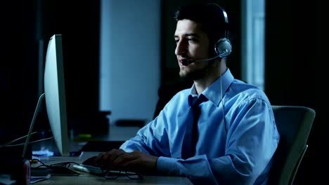 Un-hombre-joven,-que-trabaja-en-servicio-al-cliente-o-en-alguna-estación-de-torre-de-control-del-aeropuerto,-responde-a-las-llamadas-a-los-clientes-de-teléfono-con-una-sonrisa-día-y-noche.