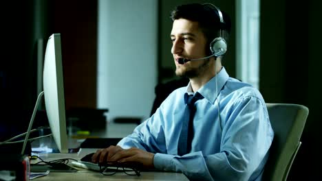 Un-hombre-joven,-que-trabaja-en-servicio-al-cliente-o-en-alguna-estación-de-torre-de-control-del-aeropuerto,-responde-a-las-llamadas-a-los-clientes-de-teléfono-con-una-sonrisa-día-y-noche.