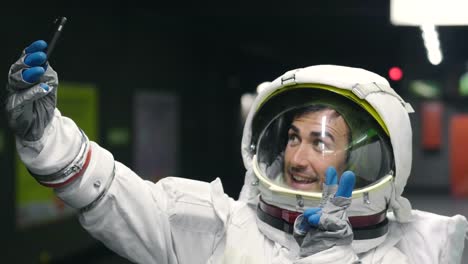 Un-hombre-vestido-de-astronauta-utiliza-el-smartphone-para-llamar-y-enviar-mensajes.-Las-sonrisas-de-astronauta-mirando-el-teléfono-en-la-mano.