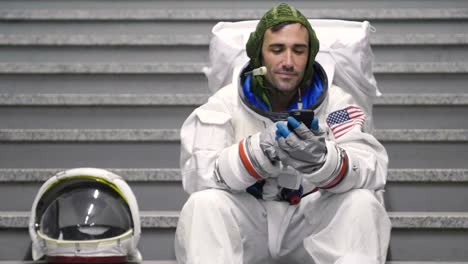 Ein-Astronaut-gekleidet-Mann-nutzt-das-Smartphone-anrufen-und-Nachrichten-senden.-Der-Astronaut-lächelt-beim-Betrachten-des-Telefons-in-der-Hand.