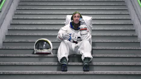 Un-hombre-vestido-de-astronauta-utiliza-el-smartphone-para-llamar-y-enviar-mensajes.-Las-sonrisas-de-astronauta-mirando-el-teléfono-en-la-mano.