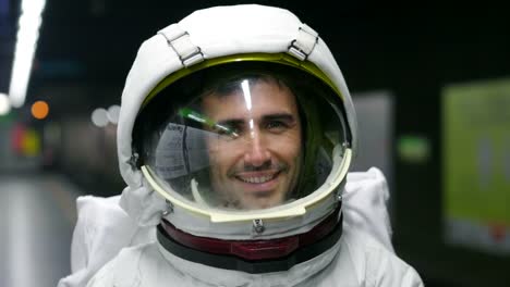 An-astronaut-dressed-man-uses-the-smartphone-to-call-and-send-messages.-The-astronaut-smiles-while-looking-at-the-phone-in-his-hand.