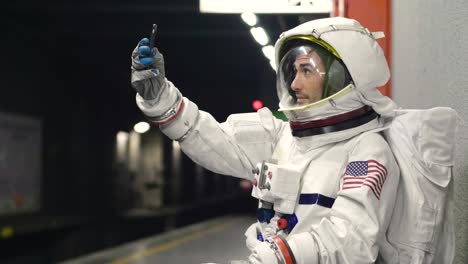 An-astronaut-dressed-man-uses-the-smartphone-to-call-and-send-messages.-The-astronaut-smiles-while-looking-at-the-phone-in-his-hand.