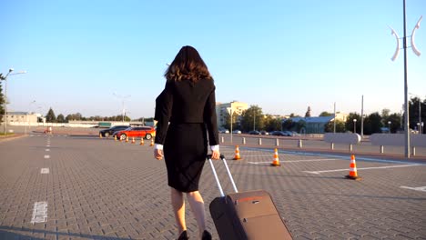Business-woman-going-to-taxi-parking-from-the-airport-with-her-suitcase.-Lady-walking-with-her-suitcase-along-street.-Travel-concept.-Side-view-Slow-motion-Close-up