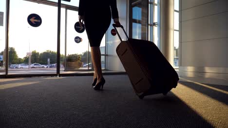 Business-Dame-mit-ihrem-Gepäck-zum-Flughafen-gehen.-Frau-in-Heels-zu-Fuß-mit-ihrem-Koffer-vom-Terminal-zur-Stadtstraße.-Mädchen-treten-und-Trolley-auf-Rädern.-Reise-Konzept.-Slow-Motion-hautnah