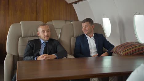 Businesspeople-discussing-inside-business-private-jet-armchairs