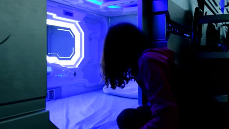 Woman-looks-with-surprise-at-the-Sleepbox-with-neon-lights,-the-space-capsule-container-for-sleeping-at-the-airport