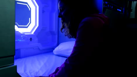 Woman-examines-the-Sleepbox-with-neon-lights,-a-space-capsule-container-for-sleeping-at-the-airport