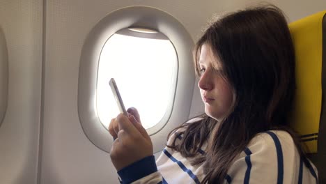 Teenager-girl-uses-smartphone-on-plane