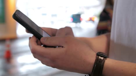 Close-up-shot-of-hands-using-smartphone-app-to-call-ride-share-car-at-airport