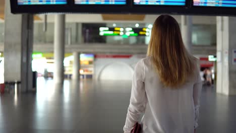 Cute-blonde-girl-in-casual-clothes-is-sad-in-an-empty-airport-terminal-and-looks-into-the-camera