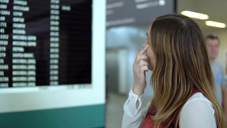 Bastante-joven-mujer-está-parado-cerca-del-marcador-con-el-vuelo-número-aviso-y-elección.