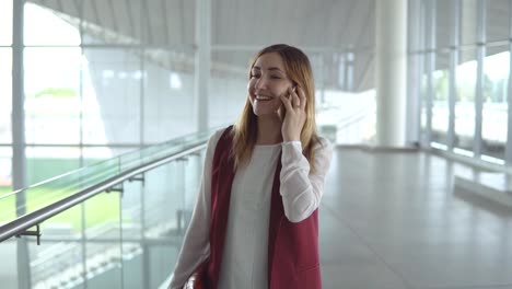 Positivo-habla-de-mujer-joven-en-ropa-elegante-smartphone-mientras-que-embarque-en-el-avión-en-el-aeropuerto