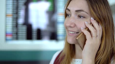 Junges-Mädchen-in-eleganten-Kleidern-lächelnd-spricht-auf-Smartphone-am-Flughafen.