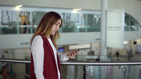 young-girl-in-elegant-clothes-stands-and-typing-in-the-smartphone-in-the-airport