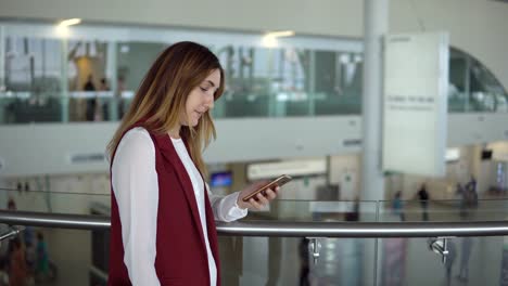 junges-Mädchen-in-eleganten-Kleidern-Ständen-und-Eingabe-in-das-Smartphone-am-Flughafen