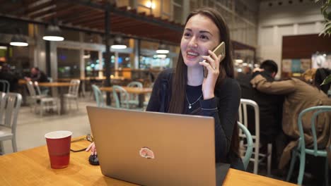 Junge,-schöne-Mädchen-arbeiten-mit-Laptop-und-Kaffeetrinken-an-einem-Holztisch