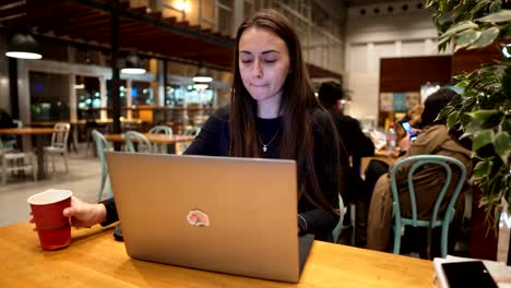 Junge,-schöne-Mädchen-arbeiten-mit-Laptop-und-Kaffeetrinken-an-einem-Holztisch