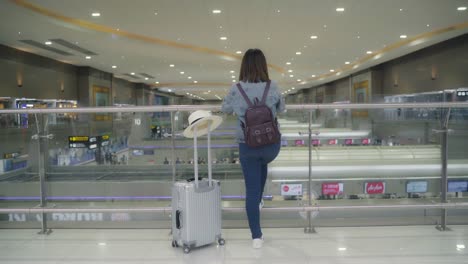 Happy-Asian-woman-using-trolley-or-cart-with-many-luggage-walking-in-terminal-hall-while-going-to-boarding-flight-at-the-departure-gate-in-international-airport.-Women-happy-in-the-airport-concept.