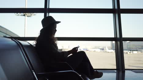 Junge-Frau-mit-Smartphone-in-Flughafen