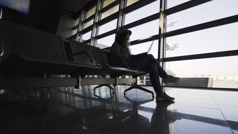 Woman-with-laptop-on-bench-in-airport