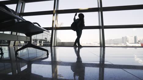 Woman-with-backpack-taking selfie-on-smartphone-in-airport