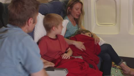 Familia-metiendo-en-los-niños-a-dormir-en-el-avión