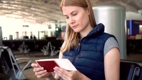 Beautiful-young-woman-at-the-airport.-Waiting-for-her-flight.-Checking-passport-and-boarding-pass