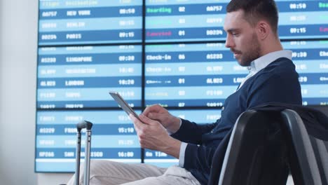 Man-using-Tablet-while-Waiting-Boarding-at-Departure-Lounge-at-the-Airport.