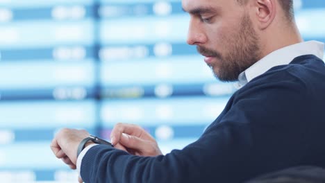 Man-looking-at-and-using-Smart-Watch-while-Waiting-Boarding-at-Departure-Lounge-at-the-Airport.