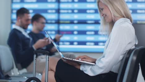 Attraktive-Adult-Business-Frau-mit-Laptop-beim-Boarding-warten-am-Abflug-Lounge-am-Flughafen.