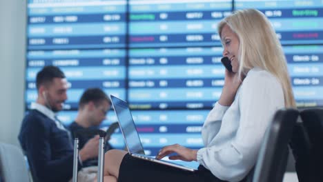 Attractive-Adult-Business-Woman-Talking-on-the-Phone-while-Waiting-Boarding-at-Departure-Lounge-at-the-Airport.