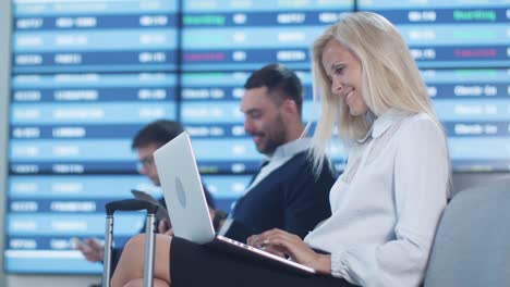 Attraktive-Adult-Business-Frau-mit-Laptop-beim-Boarding-warten-am-Abflug-Lounge-am-Flughafen.