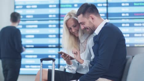 Mann-und-Frau,-die-Phone-Together-beim-Warten-in-der-Departure-Lounge-am-Flughafen-nutzen.