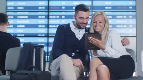 Man-and-Woman-using-Phone-Together-while-Waiting-Boarding-at-Departure-Lounge-at-the-Airport.