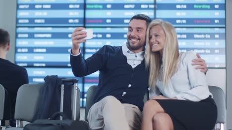 Hombre-y-mujer-hacer-Selfie-Pictures-con-el-teléfono-mientras-espera-el-embarque-en-la-sala-de-salida-en-el-aeropuerto.