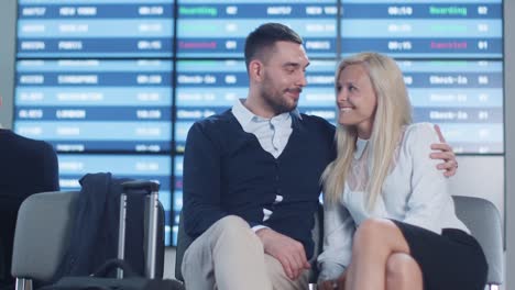 Mann-und-Frau-sprechen,-während-Boarding-warten-am-Abflug-Lounge-am-Flughafen.