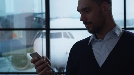 Geschäftsmann-mit-Handy-in-der-Abfluglounge-am-Flughafen.