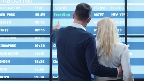 Caucasian-Ethnicity-Man-and-Woman-Looking-at-Information-Board-at-the-Airport.