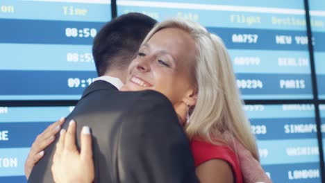 Man-and-Woman-meeting-in-the-Airport-Arrival-Hall.-People-are-Hugging-each-other-and-Smiling.