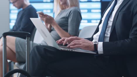 Hombre-de-negocios-trabajando-en-ordenador-portátil-mientras-espera-el-embarque-en-la-sala-de-embarque-en-el-aeropuerto.