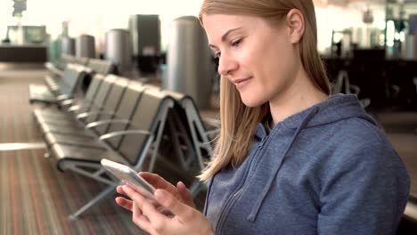 Schöne-Frau-mit-Smartphone-im-Flughafen.-Surfen-Internet,-kommunizieren-mit-ihren-Freunden