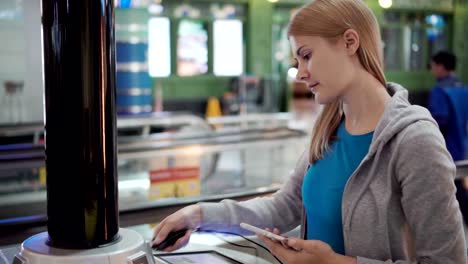 Hermosa-mujer-atractiva-en-la-terminal-del-aeropuerto.-De-pie-cerca-de-carga-soporte-de-pluging-en-smartphone