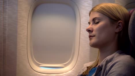 Beautiful-woman-sleeping-near-airplane-window-during-turbulence.-Long-distance-flight.-Shaky-image