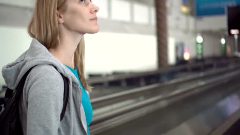 Hermosa-mujer-atractiva-en-la-terminal-del-aeropuerto.-A-la-espera-para-el-vuelo.-Utilizando-travolator,-mirando-a-su-alrededor