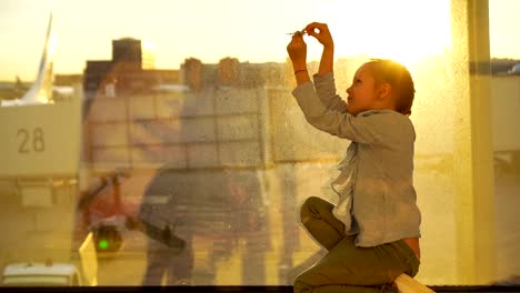 Adorable-little-girl-playing-with-small-model-airplane-in-airport-waiting-for-boarding