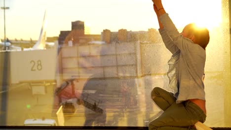 Adorable-little-girl-playing-with-small-model-airplane-toy-in-airport-near-big-window.-Concept-of-flying-and-airplane.